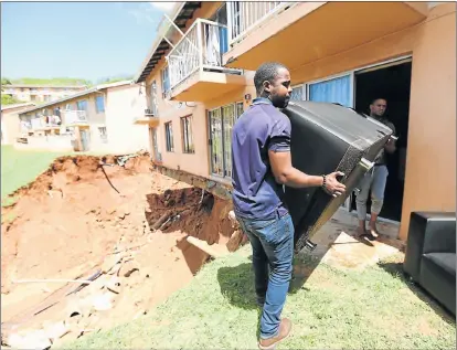  ?? Picture: JACKIE CLAUSEN ?? STORM DAMAGE: People help to carry furniture out of damaged flats in the Northridge Park Complex in Woodlands, south of Durban, where the stormwater washed away the soil beneath the flats and crushed a house below it