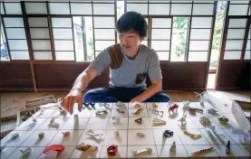  ?? QUENTIN TYBERGHIEN / AGENCE FRANCE-PRESSE ?? Yuki Tatsumi sits next to his collection of origami made from chopstick sleeves in Kameoka, Kyoto prefecture, on May 23.