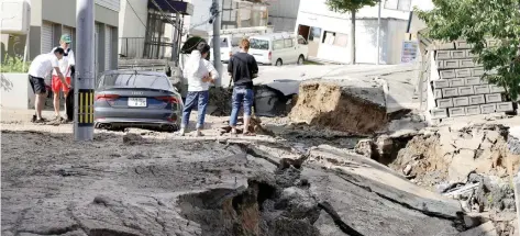  ??  ?? Residentes observan una calle dañada en la ciudad de Sapporo, en Hokkaido, tras el movimiento telúrico que afectó esta isla japonesa, y que causó deslaves.