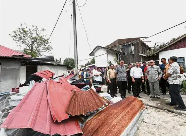  ?? — Bernama ?? On the scene: Dr Mahathir checking homes destroyed in a storm at Kampung Kuala Melaka after visiting the temporary shelter at SK Kuala Teriang.