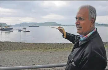  ?? 16_t23_WalkingTou­r01/04 ?? Oban town tour guide Farooq explains the history of Kerrera and the landmark ‘dogstone’.