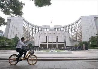  ?? CHEN XIAOGEN / FOR CHINA DAILY ?? A cyclist pedals past the headquarte­rs of the People’s Bank of China in Beijing.
