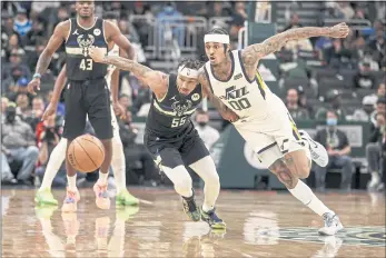  ?? JEFFREY PHELPS — THE ASSOCIATED PRESS ?? Milwaukee Bucks guard Justin Robinson (55) and Utah Jazz guard Jordan Clarkson (00) reach for the ball during the second half Sunday in Milwaukee.