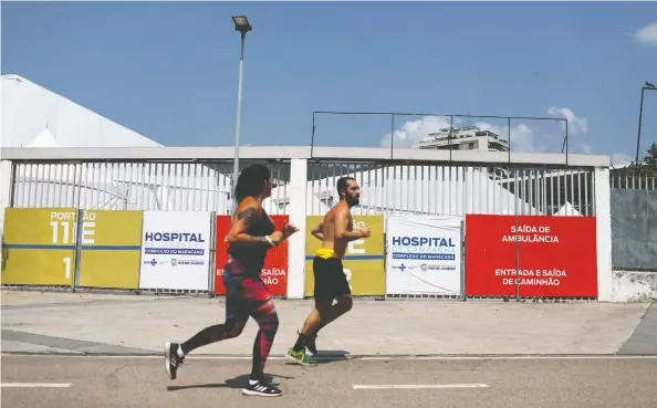  ?? PILAR OLIVARES/REUTERS ?? Joggers pass the Maracana campaign hospital earlier this month in Rio de Janeiro amid the COVID-19 pandemic which has killed 139,000 Brazilians.