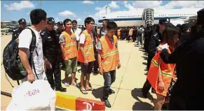  ??  ?? Heading home: The suspects (in orange vests) being escorted by Chinese police before boarding at Phnom Penh Internatio­nal Airport. — AP