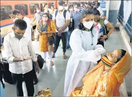  ??  ?? A healthcare worker collects swab samples of passengers at Dadar station, on Thursday.