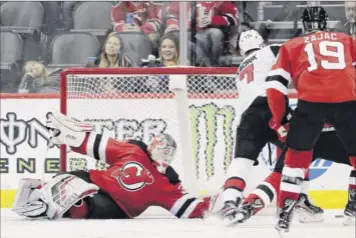  ?? Julio Cortez / Associated Press ?? New Jersey goaltender Cory Schneider, left, falls to the ice while reaching to defend against Ottawa left wing Brady Tkachuk during the second period Thursday.