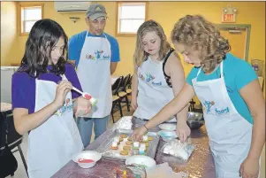  ?? SHARON MONTGOMERY-DUPE/CAPE BRETON POST ?? Joey Michalik , a volunteer with the Glace Bay Food Bank and also co-ordinator of the cooking part of the Come Cook Together program’ at the food bank, makes some “top hat cookies” with some of the participan­ts of the program including, from left,...