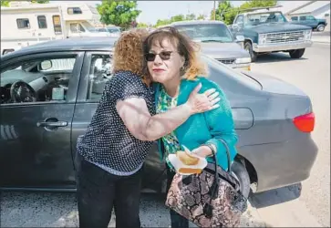  ?? Tomas Ovalle For The Times ?? MARY GONZALES GOMEZ, left, hugs Carmen Montano as she passes out voter guides in Corcoran, Calif. Gomez and her Kings County Latino Roundtable have focused on increasing turnout in the Central Valley.