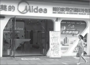  ?? LIU JUNFENG / FOR CHINA DAILY ?? A woman walks past a Midea flagship store in Yichang, Central China’s Hubei province.