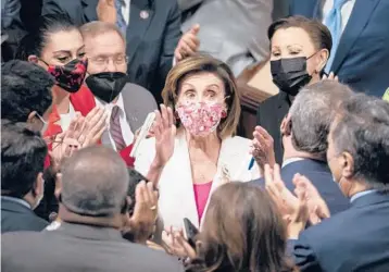  ?? J. SCOTT APPLEWHITE/AP ?? Speaker Nancy Pelosi, center, celebrates with Democratic lawmakers on Friday after the House voted.