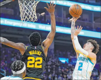  ?? Jeff Chiu The Associated Press ?? Hornets guard Lamelo Ball lines up a shot over Warriors forward Andrew Wiggins in the first half of Golden State’s 114-92 victory Wednesday at Chase Center.