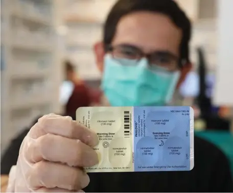  ?? TNS FILE ?? IN STOCK: SureCare Pharmacy manager Oscar Uribe shows off a package of Pfizer Paxlovid pills at Esperanza Health Center in Chicago. Pfizer’s Paxlovid is a treatment for COVID-19.