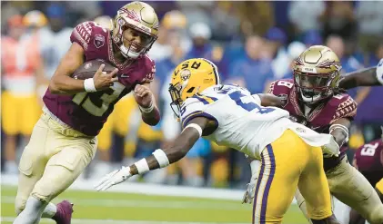  ?? GERALD HERBERT/AP ?? Florida State quarterbac­k Jordan Travis runs with the ball as LSU safety Jay Ward tries to bring him down during a game last season. The teams will meet again Sunday night to open this season.