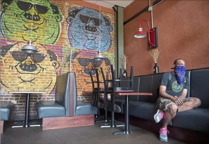  ?? Emily Matthews/Post-Gazette ?? Averill “Apple” Grimes, the kitchen manager at Fat Head’s Saloon, sits in the empty restaurant Saturday on the South Side. Fat Head’s was still taking to-go orders, but Mr. Grimes said it was not nearly as busy as it usually is on the Fourth of July.