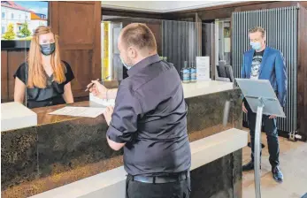  ?? FOTO: AH ?? Das Rezeptions­personal und der Hoteldirek­tor des Bodensee-Hotel Sonnenhof in Kressbronn-Rettersche­n, Thomas Riethmülle­r (rechts), testen die Abläufe beim Betreten und Einchecken des Hauses.
