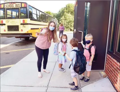  ?? Peter Hvizdak / Hearst Connecticu­t Media ?? Teacher Samantha Celentano guides children to the proper entrance at Melissa Jones Elementary School in Guilford on Wednesday. Below, Eleanor Finch, 6, gets a hug from her mother, Danielle Finch, with dog Maeby.