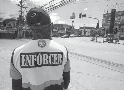  ?? Photo by Jean Nicole Cortes ?? ALMOST EMPTY. A traffic enforcer stares at an almost empty street along Km. 5 in La Trinidad, Benguet after the town was placed under extreme enhanced community quarantine on March 30 to 31. On a regular day, the area is usually crowded.