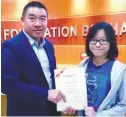  ??  ?? Kuok Foundation general manager TS Ng presents a scholarshi­p to LF Wong.