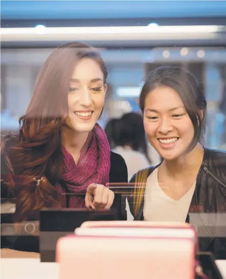  ??  ?? Megan Hoeneveld (left) and Michelle Sim checking out bags at an Oroton store. Picture: MATTHEW POON