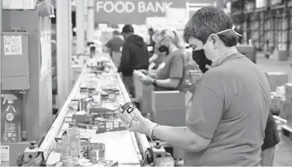  ?? BRIAN KRISTA/BALTIMORE SUN MEDIA ?? Maria Engelbrech­t, of Columbia, sorts items on a conveyor belt at the Maryland Food Bank on March 25.