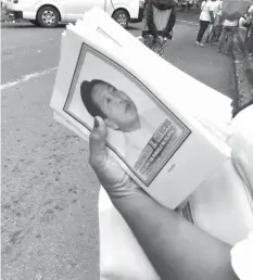  ??  ?? A woman holds booklets with the portrait of the late dictator Ferdinand Marcos on the cover at what is billed as a "general assembly" of a "cooperativ­e" at UP-Los Baños.