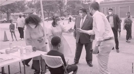  ??  ?? Gov. J. B. Pritzker chats with medical personnel during a visit in July to a mobile COVID- 19 testing station at Edward Coles School in the South Chicago neighborho­od.