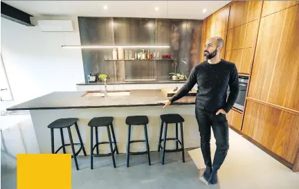  ?? PHOTOS: JOHN MAHONEY ?? Ali Shams in the kitchen of the home he shares with his partner in a century-old triplex. The backsplash is raw steel and the cabinets, with no handles, are indicative of the home’s clean design.