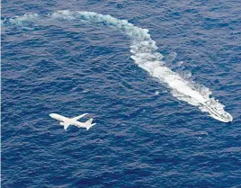  ?? Kyodo News via AP ?? ■ Japan’s Coast Guard ship, top, and U.S. military plane are seen Thursday at sea off Kochi, southweste­rn Japan, during the search and rescue operation for missing crew members of the U.S. Marine refueling plane and fighter jet.