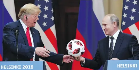  ?? YURI KADOBNOV / AFP / GETTY IMAGES ?? Russian President Vladimir Putin gives a World Cup soccer ball to U.S. President Donald Trump at a press conference in Helsinki, Finland, on Monday.