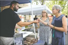  ?? BEA AHBECK/NEWS-SENTINEL ?? Vicia’s co-owner Gabriel DeAnda hands samples to Linda Marino, of Oakdale, and Lynne Smith, of Lodi, at their booth at the farmers market in Downtown Lodi on Thursday.