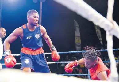  ?? IAN ALLEN ?? Jerone Ennis (left) of the Jamaica Defence Force looks on as Malcolm Peck of G.C. Foster College goes down during their super middleweig­ht clash at the Wray and Nephew-sponsored Fight Night at the Arnett Gardens Sports Complex on August 12, 2023.
