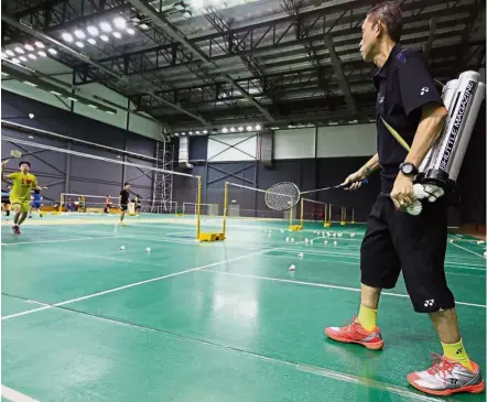  ??  ?? Ready, let’s go: Datuk Misbun Sidek with the shuttlecoc­k tubes neatly bound and slung over his shoulder during a training session with Tan Jia Wei at Bukit Kiara. — GLENN GUAN / The Star