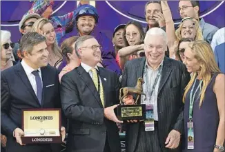  ?? Diane Bondareff ?? HORSE enthusiast Hughes, third from left, receives recognitio­n from timepiece maker Longines in 2016 at Santa Anita Park after his horse Beholder won the Longines Breeders’ Cup Distaff.