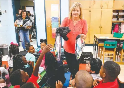  ?? STAFF PHOTO BY DOUG STRICKLAND ?? Kelley Andrews hands out backpacks to students at Calvin Donaldson Environmen­tal Science Academy on Tuesday. Volunteers from The Back to School community outreach collaborat­ive, The Nehemiah Project, and The Bethlehem Center delivered hundreds of backpacks to the elementary school and other Title I schools.