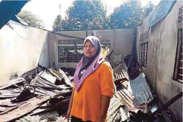  ??  ?? SITI Noraisikin melihat keadaan rumahnya yang hangus dalam kebakaran di FELDA Jengka 17, semalam.