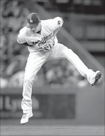  ?? Allen J. Schaben Los Angeles Times ?? DODGERS SHORTSTOP Manny Machado, who doubled home a run in the eighth inning, leaves his feet to corral a bouncer by San Francisco Giants catcher Buster Posey in the fourth.