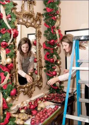  ??  ?? Clara Carroll of Searcy decorates with garland around a mirror
in the Governor’s Mansion entryway.