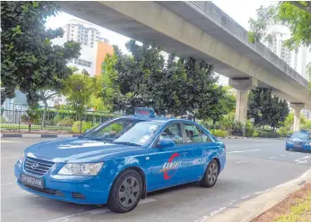  ?? FOTOS: AFP ?? Blaue Taxis eines Unternehme­ns in Singapur sind häufiger in Unfälle verwickelt als gelbe.