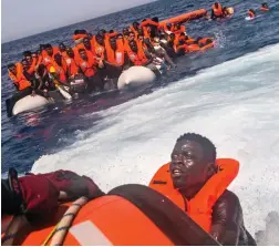  ??  ?? End of an ordeal: A migrant is saved as others wait their turn