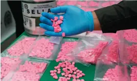  ?? AP FILE PHOTO ?? A police officer shows seized MDMA tablets, also known as ecstasy, during a media presentati­on at the El Dorado Airport in Bogota, Colombia. Scientists found exposure to MDMA made octopuses more inclined to touch each other.
