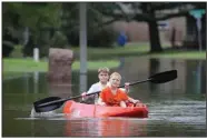  ?? (AP/Houston Chronicle/Steve Gonzales) ?? Josey Chambers, 11, and his brother Sawyer, 7, make their way on a kayak up Wandering Trail after Clear Creek in Friendswoo­d, Texas, overflowed Tuesday from rain from Tropical Storm Beta.