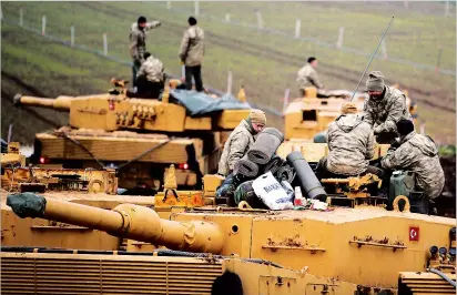 ??  ?? Turkish soldiers on top of their tanks near the Turkish-Syrian border in Hatay province