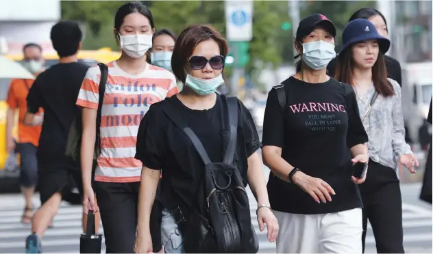  ?? Associated Press ?? ↑
People, wearing face masks, walk on a street in Taipei on Saturday.