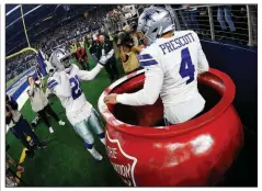  ?? AP/RON JENKINS ?? Dallas Cowboys quarterbac­k Dak Prescott celebrates after being lifted into a Salvation Army kettle by running back Ezekiel Elliott following his touchdown against the Washington Redskins on Nov. 22 in Arlington, Texas. Elliott was fined $13,369 on Saturday for placing both money and Prescott in the kettle.