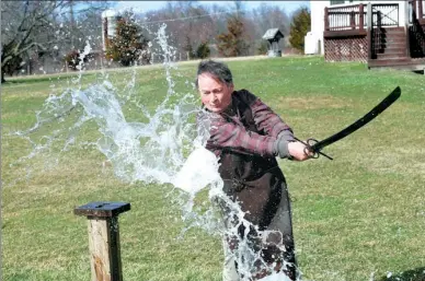  ?? SETH WENIG / ASSOCIATED PRESS ?? John Lundemo demonstrat­es the sharp edge on one of his swords by slicing through a water jug at his workshop in New Hampton, New York.