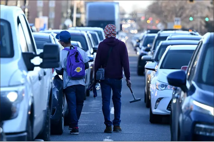  ?? PHOTOS BY HELEN H. RICHARDSON — THE DENVER POST ?? Venezuelan migrants, who did not want to be identified, try to make money cleaning windshield­s at stoplights on Colorado Boulevard and Colfax Avenue in Denver on Jan. 30.