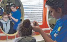  ??  ?? Wie eine Haarmessun­g funktionie­rt, erlebt die Schülerin am eigenen Kopf.