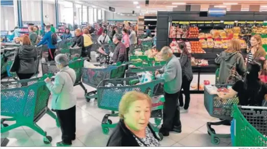  ?? MARCIAL GUILLÉN / EFE ?? Decenas de personas hacen cola ante las cajas de un supermerca­do en el día de ayer.