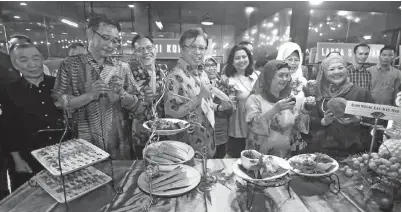  ?? ‘Experience Sarawak’ ?? ABANG JOHARI (tengah) bersama isteri, Datin Patinggi Datuk Amar Juma’ani Tuanku Bujang (tiga kanan), Karim (dua kiri), Fatimah (dua kanan) serta tetamu kehormat lain menunjukka­n antara makanan tradisi Sarawak yang dipamerkan sempena di Kopi O’ Corner.